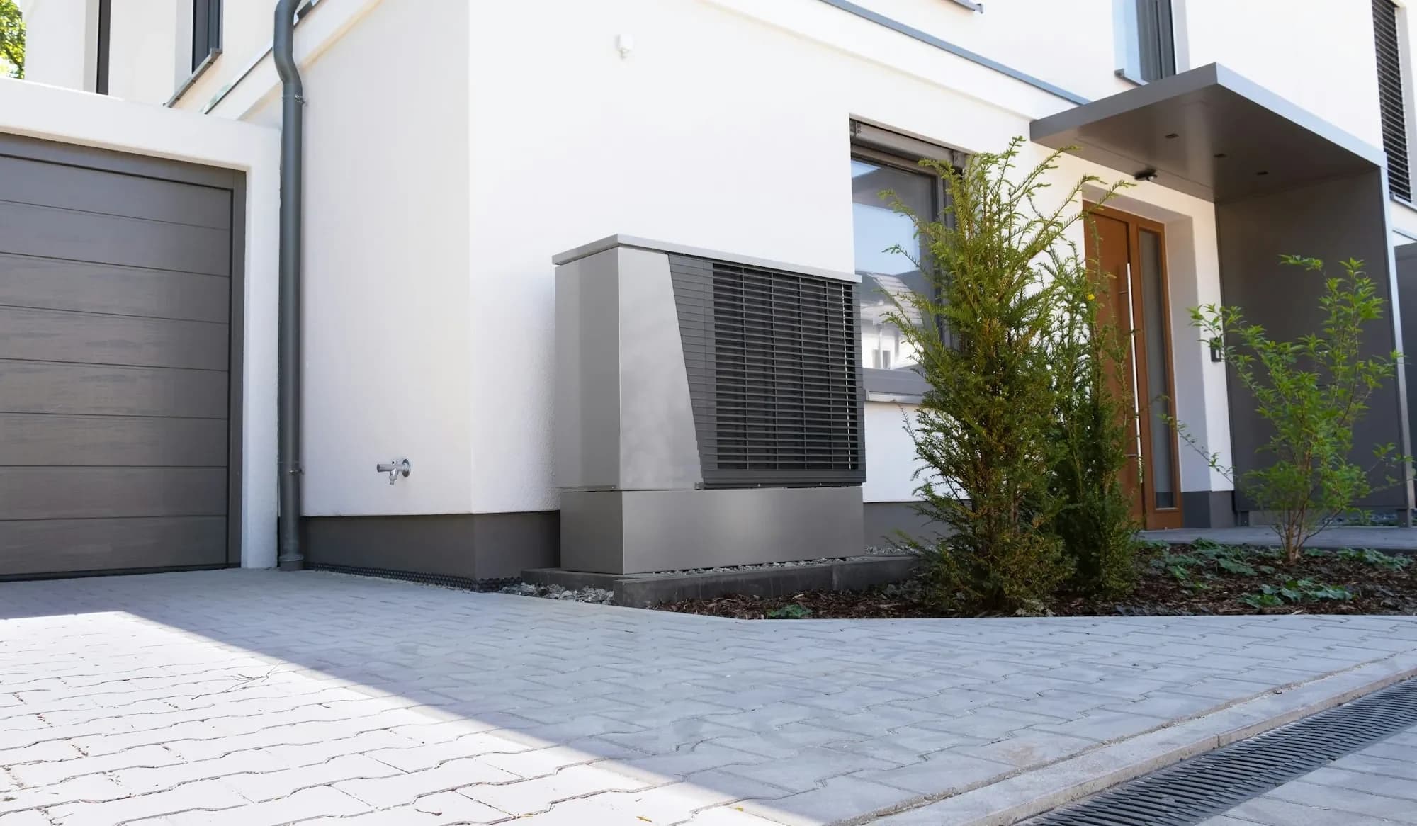 Außengerät einer Luft-Wasser-Wärmepumpe vor einem Einfamilienhaus